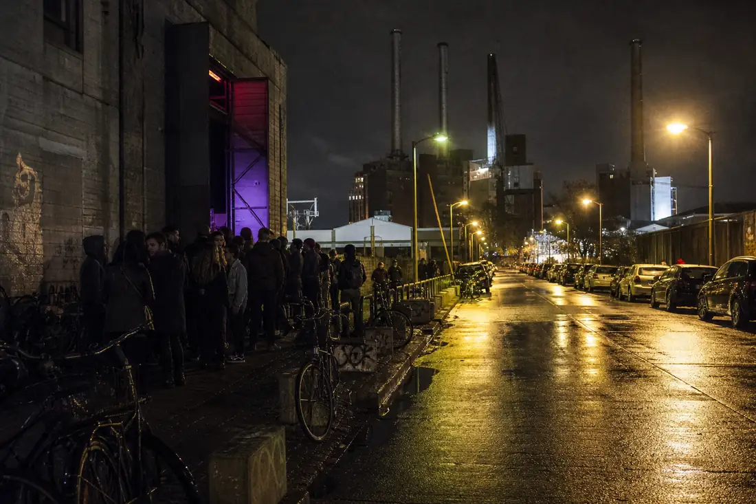Berlini klubsor betonépület előtt, sorban álló emberek